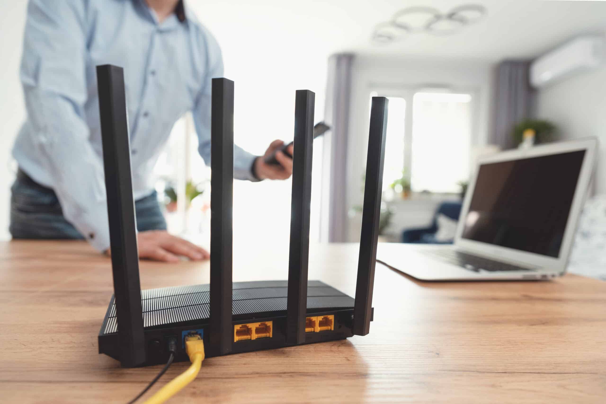 Man using modern wi-fi router on light table in room Man using modern wi-fi router on light table in room